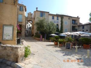 uma rua com edifícios, mesas e guarda-sóis em Maison Vacances Mer em Bages