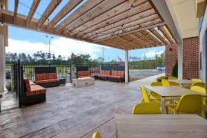 patio ze stołami i krzesłami oraz drewnianą pergolą w obiekcie Home2 Suites By Hilton Charlotte Northlake w mieście Charlotte