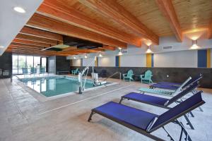 an indoor pool with blue lounge chairs and a pool at Home2 Suites By Hilton Taylor Detroit in Taylor