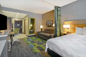 a hotel room with a bed and a couch at Home2 Suites By Hilton Taylor Detroit in Taylor