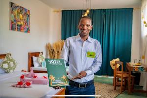 un hombre sosteniendo un cartel de hotel en una habitación en Haber Hotel & SPA en Matemwe