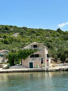 a stone house on the shore of a body of water at Holiday House Val with sea view in Pašman