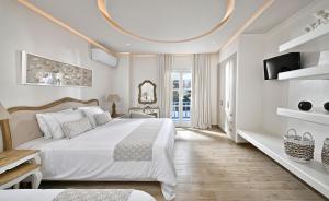 a white bedroom with a large bed and a tv at Erato Hotel Mykonos in Ornos