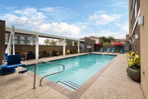 a swimming pool in a hotel with chairs and tables at Home2 Suites By Hilton Phoenix Airport North, Az in Phoenix
