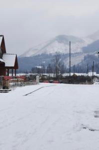 un aparcamiento cubierto de nieve con una montaña en el fondo en Apartmán 111 Vila Zuberec, en Zuberec