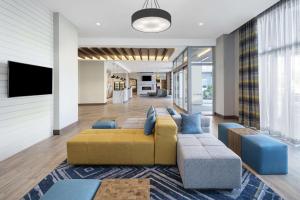 a living room with a yellow couch and blue chairs at Homewood Suites by Hilton Boston Woburn in Woburn