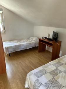 a room with two beds and a desk with a television at Holiday House Val with sea view in Pašman