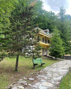 a green park bench sitting in front of a house at Bujtina Te Grima in Theth