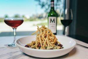 un plato blanco de pasta con una copa de vino en The Axis Moline Hotel, Tapestry Collection By Hilton, en Moline