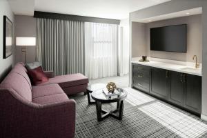 a living room with a couch and a tv at The Axis Moline Hotel, Tapestry Collection By Hilton in Moline