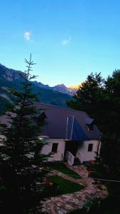 Casa blanca con techo púrpura y árboles en Bujtina Te Grima, en Theth
