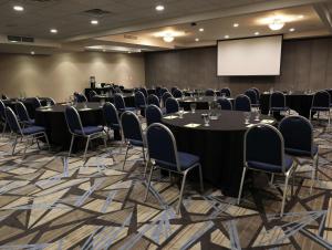 una sala de conferencias con mesas, sillas y una pantalla en Doubletree By Hilton Omaha Southwest, Ne, en Omaha