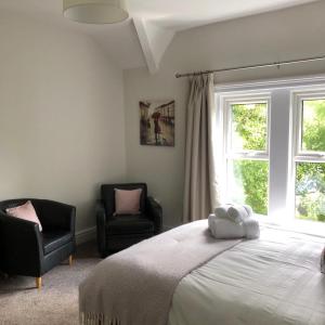 a bedroom with a bed and two chairs and a window at Comfy big 7 bedroom townhouse in Harrogate