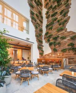 a restaurant with tables and chairs and a large wall with plants at Canopy West Palm Beach - Downtown in West Palm Beach