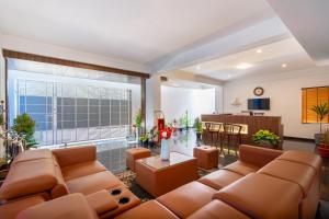 een woonkamer met bruin meubilair en een groot raam bij The Silver Chimes Suites in Bangalore