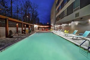 ein großer Pool mit Stühlen und ein Gebäude in der Unterkunft Home2 Suites By Hilton Lawrenceville Atlanta Sugarloaf, Ga in Lawrenceville