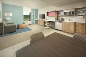 Home2 Suites By Hilton Atlanta Nw/Kennesaw, Ga في كينيساو: مطبخ وغرفة معيشة مع طاولة وأريكة