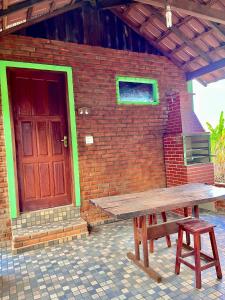 eine Holzbank vor einem Backsteingebäude mit einer Tür in der Unterkunft Sítio do pica pau amarelo in São Thomé das Letras