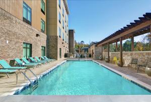 a swimming pool with lounge chairs next to a building at Home2 Suites By Hilton Charleston Daniel Island, Sc in Charleston