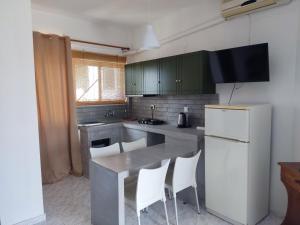 a kitchen with green cabinets and a table with white chairs at ThalaSEA Apartments in Chrani