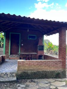 ein Backsteinhaus mit einer Holztür und einer Terrasse in der Unterkunft Sítio do pica pau amarelo in São Thomé das Letras