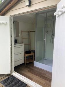 La salle de bains est pourvue d'une douche et d'une porte en verre. dans l'établissement Le Châlet des Hortillonnages, à Amiens