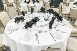 une table pour un mariage avec des tables blanches et des serviettes noires dans l'établissement Hilton Garden Inn Wichita Downtown, Ks, à Wichita