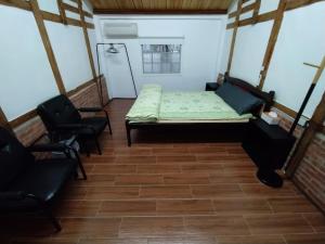 Habitación pequeña con 1 cama y 2 sillas en 順耆自然Shun Ci Zih Ran, en Xingang