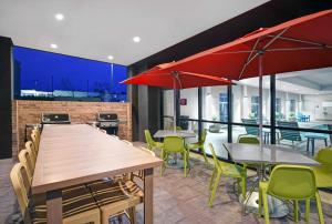 a restaurant with tables and chairs and red umbrellas at Home2 Suites by Hilton Liberty NE Kansas City, MO in Liberty