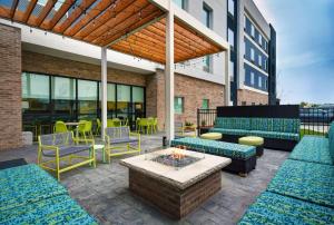 eine Terrasse mit Sofas, Stühlen und einer Feuerstelle in der Unterkunft Home2 Suites by Hilton Liberty NE Kansas City, MO in Liberty