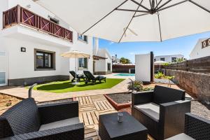 a patio with chairs and an umbrella and a yard at Siesta Suites Lanzarote in Yaiza