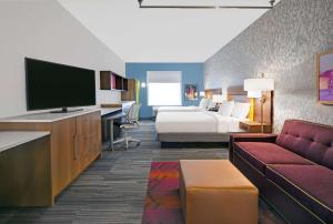 a hotel room with a bed and a tv and a couch at Home2 Suites by Hilton Liberty NE Kansas City, MO in Liberty