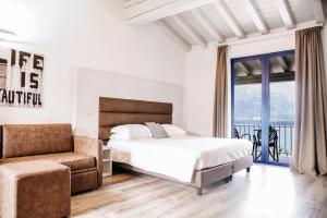 a bedroom with a bed and a chair and a window at Bella Hotel & Restaurant with private dock for mooring boats in San Felice del Benaco