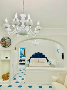 a white bedroom with a bed and a chandelier at Villa Dei Principi in Positano
