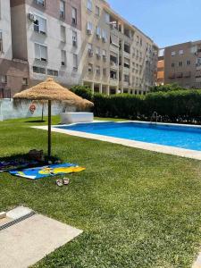 una piscina con sombrilla y una tabla de surf en la hierba en Piso en zona teatinos by Centric, en Málaga