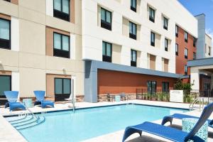 a swimming pool with chairs and a building at Hampton Inn Clewiston in Clewiston