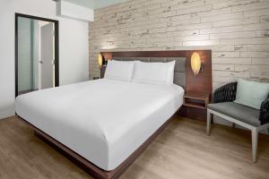 a bedroom with a large white bed and a chair at The Fin Hotel, Tapestry Collection by Hilton in Oceanside