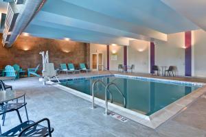 una piscina en un hotel con sillas y mesas en Home2 Suites Williston Burlington, Vt en Williston