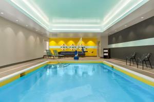 una piscina in una camera d'albergo con sedie e tavolo di Tru By Hilton Albany Airport, Ny a Latham