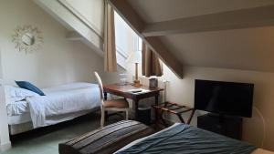 a room with a desk and a bed and a tv at LOGIS - Hôtel & Restaurant Le Gonfalon in Germigny-lʼEvêque
