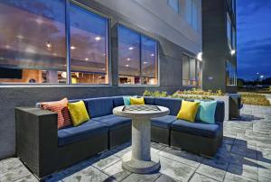 Tru By Hilton Monroe, MI في مونرو: أريكة زرقاء مع وسائد ملونة تجلس خارج المبنى