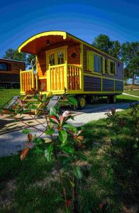 a small yellow house with a porch on the grass at Les Roulottes de la Ferme des Chanaux in Saint-Julien-dʼAnce