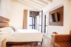 a bedroom with a bed and a tv on a wall at Bella Hotel & Restaurant with private dock for mooring boats in San Felice del Benaco