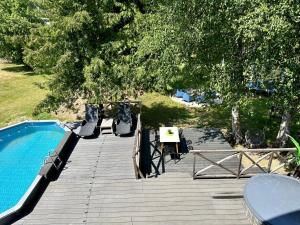 a wooden deck next to a swimming pool and trees at Semo house with sauna, pool and hot tub in Vecumnieki