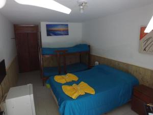 Un pequeño dormitorio con una cama azul con sábanas amarillas. en Posada San Clemente en San Clemente del Tuyú