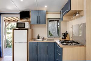een keuken met blauwe kasten en een witte koelkast bij Mobile Home Maria Marta in Barbate