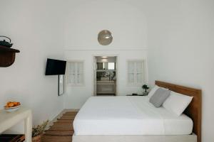 - une chambre blanche avec un lit et une télévision dans l'établissement Villa Patitiri cave house with private pool in Megalochori Santorini, à Megalochori