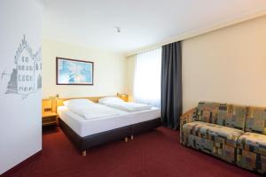 une chambre d'hôtel avec deux lits et un canapé dans l'établissement ACHAT Hotel Kaiserhof Landshut, à Landshut