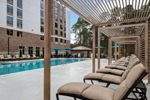 a row of lounge chairs next to a swimming pool at Hilton Garden Inn Summerville, Sc in Summerville