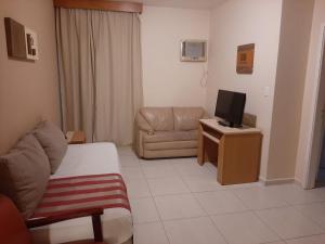 a living room with a couch and a television at Atlantico Flat Gonzaga in Santos